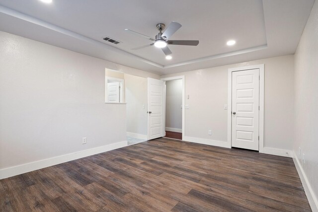 unfurnished bedroom featuring a raised ceiling, ceiling fan, and dark hardwood / wood-style flooring