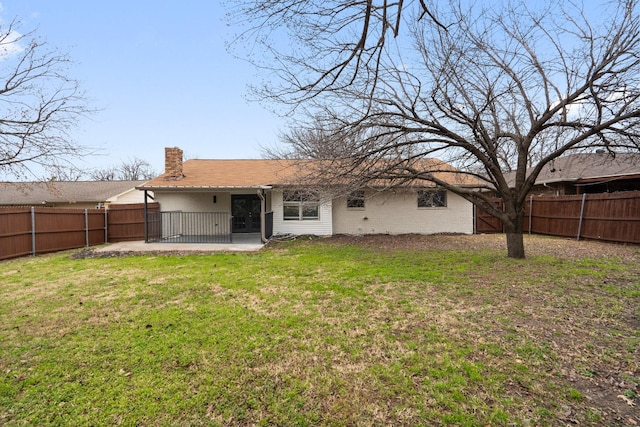 back of property featuring a patio, a yard, a chimney, and a fenced backyard