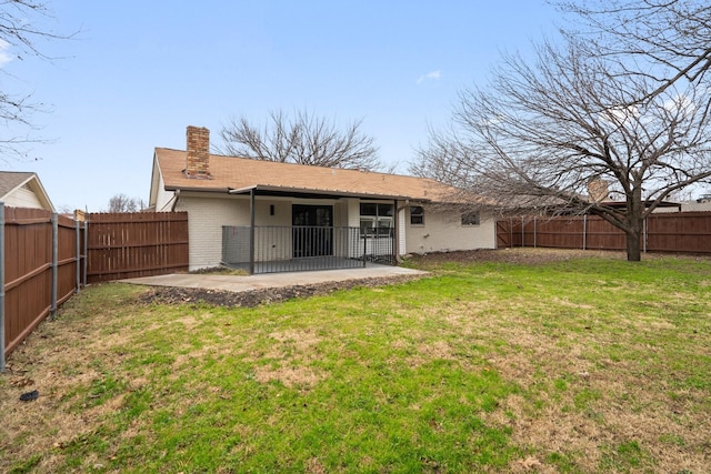 rear view of property featuring a patio, a fenced backyard, brick siding, a lawn, and a chimney