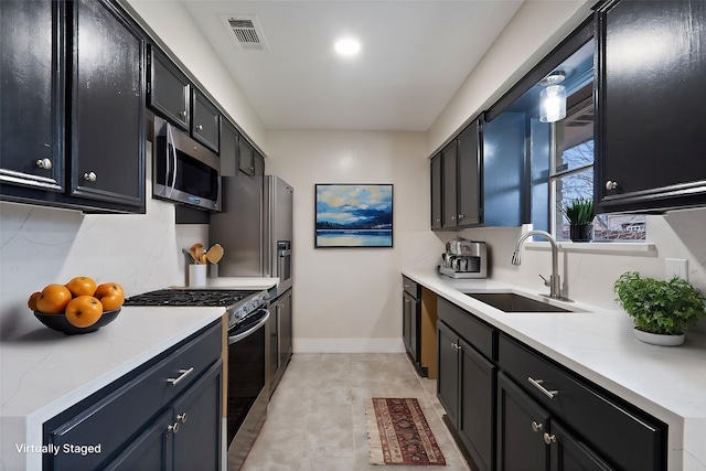 kitchen with light countertops, appliances with stainless steel finishes, a sink, and dark cabinetry