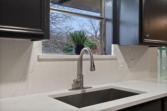 room details with light stone countertops, tasteful backsplash, and a sink