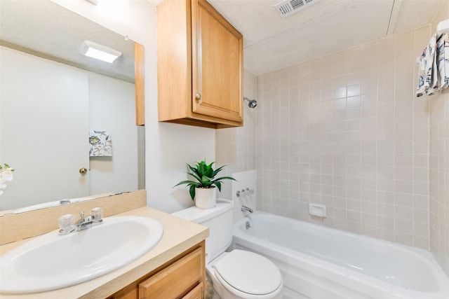 full bathroom featuring vanity, tiled shower / bath, a textured ceiling, and toilet