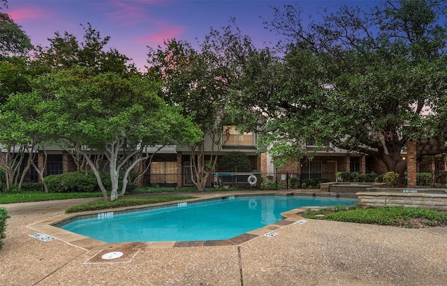 pool at dusk featuring a patio area