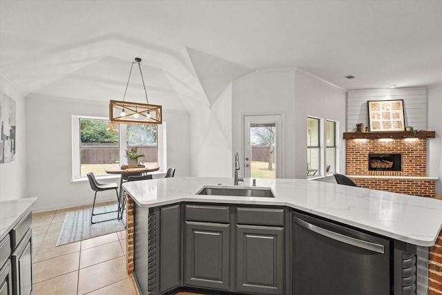 kitchen featuring pendant lighting, sink, stainless steel dishwasher, light stone counters, and a center island with sink