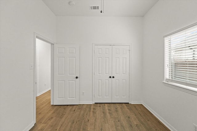 unfurnished bedroom featuring hardwood / wood-style floors and a closet