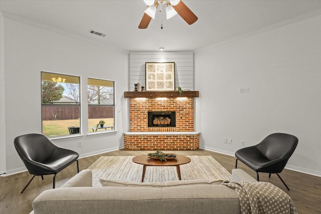 living area with ornamental molding, hardwood / wood-style floors, ceiling fan, and a fireplace