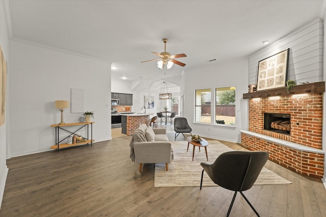 living room with sink, hardwood / wood-style flooring, ceiling fan, crown molding, and a brick fireplace