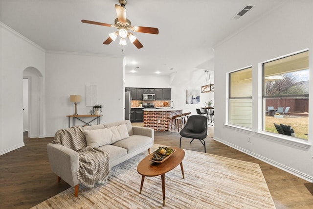 living room featuring crown molding, dark wood-type flooring, and ceiling fan