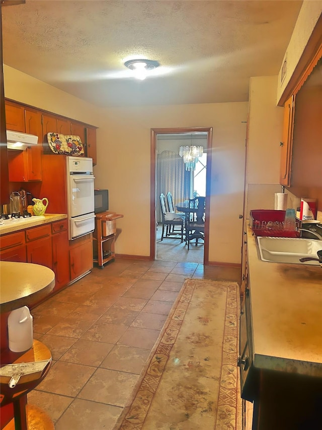 kitchen featuring light tile patterned flooring, sink, a textured ceiling, and white appliances