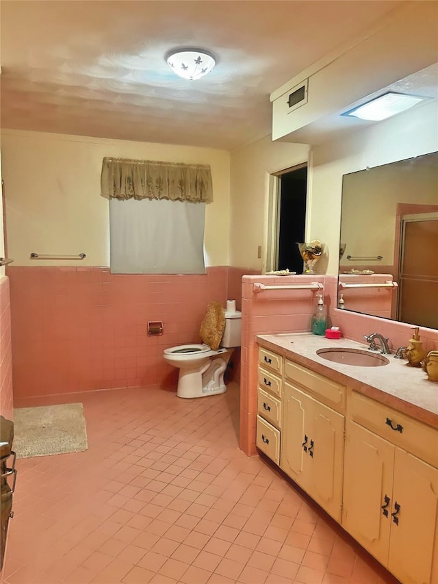 bathroom with vanity, toilet, and tile walls