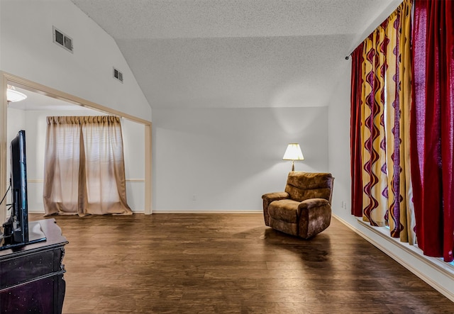 sitting room featuring hardwood / wood-style flooring, vaulted ceiling, and a textured ceiling