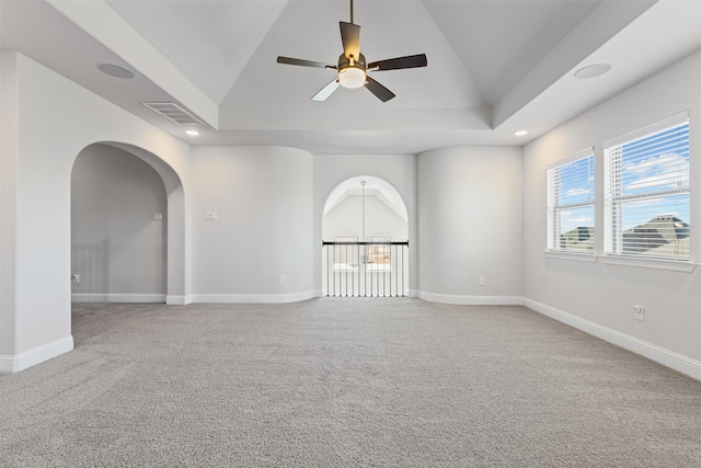 carpeted spare room with ceiling fan, lofted ceiling, and a tray ceiling