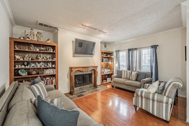 living room featuring hardwood / wood-style flooring, ornamental molding, a fireplace, and a textured ceiling