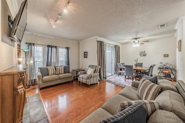 living room featuring crown molding, rail lighting, ceiling fan, light hardwood / wood-style floors, and a textured ceiling