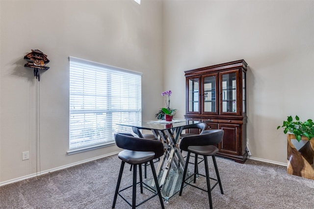 carpeted dining space with a towering ceiling