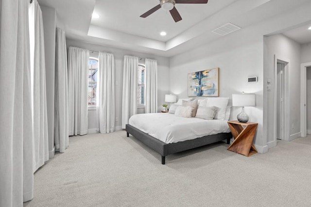 bedroom with light carpet, a raised ceiling, and ceiling fan