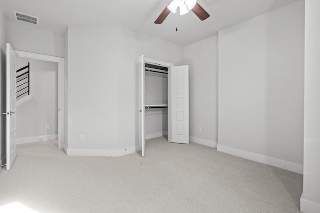 unfurnished bedroom featuring ceiling fan, light colored carpet, and a closet