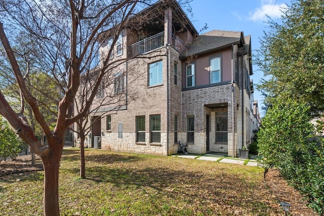 back of house with a balcony and a lawn