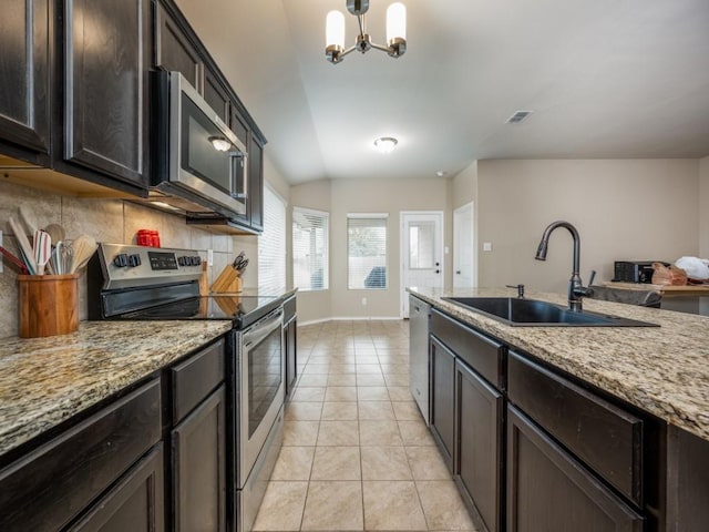 kitchen with sink, light tile patterned floors, backsplash, stainless steel appliances, and decorative light fixtures