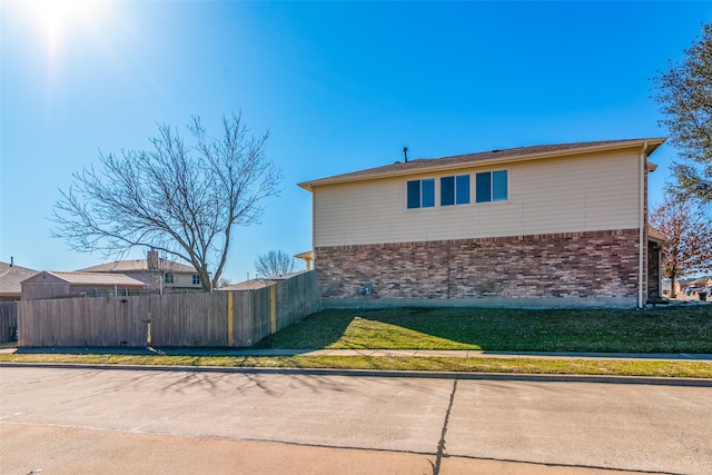 view of home's exterior featuring brick siding and fence