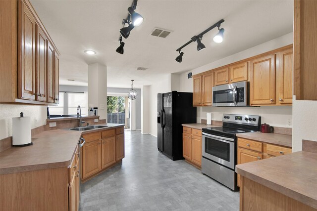 kitchen featuring pendant lighting, appliances with stainless steel finishes, sink, and a notable chandelier