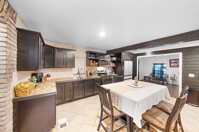 tiled dining space featuring beamed ceiling and sink