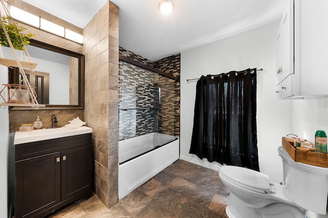 full bathroom featuring bath / shower combo with glass door, vanity, toilet, and tile walls