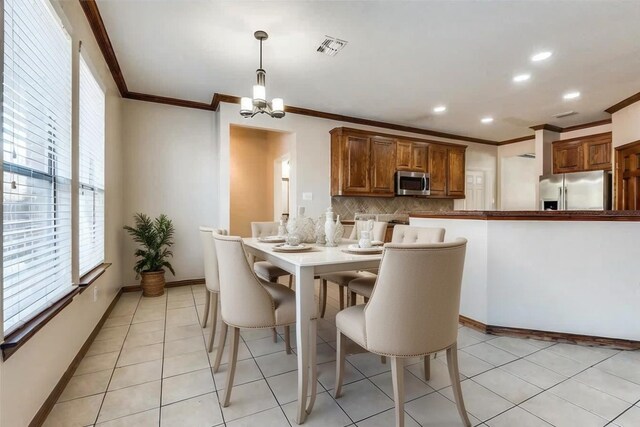 tiled dining area with crown molding and a chandelier