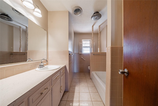 bathroom featuring a textured ceiling, tile walls, vanity, a tub, and tile patterned flooring