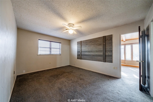 spare room featuring ceiling fan, a textured ceiling, and dark colored carpet