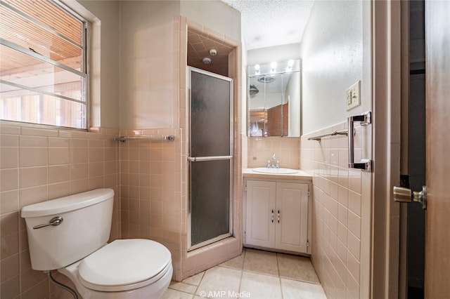 bathroom with an enclosed shower, tile walls, tile patterned floors, and a textured ceiling