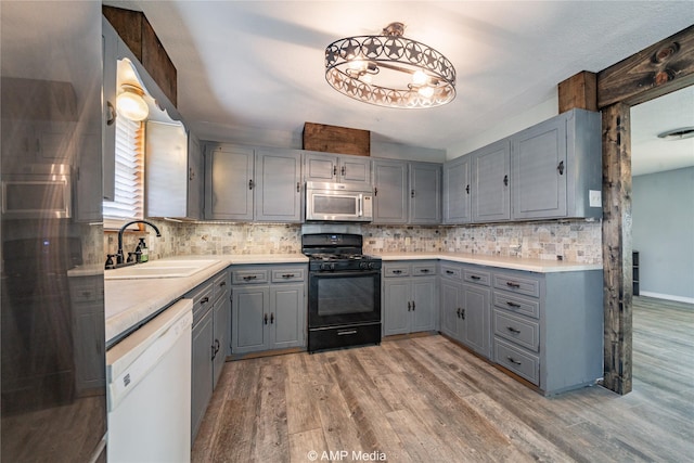 kitchen with hardwood / wood-style flooring, dishwasher, sink, and black gas stove