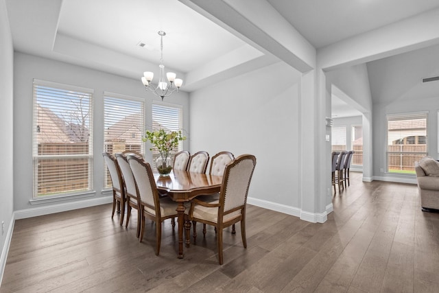 dining space featuring dark hardwood / wood-style floors, a tray ceiling, and a chandelier