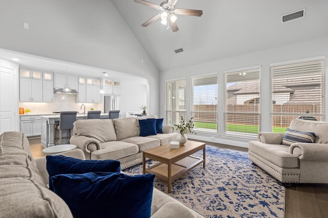 living room featuring high vaulted ceiling, light hardwood / wood-style floors, sink, and ceiling fan