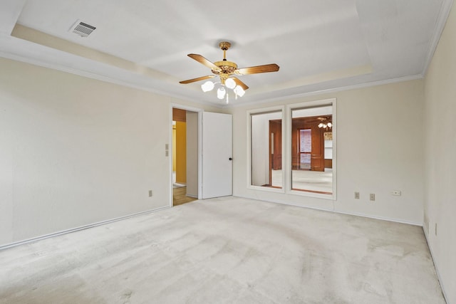 spare room featuring crown molding, a tray ceiling, light carpet, and ceiling fan