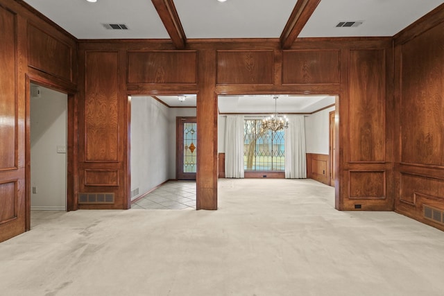 unfurnished living room with light carpet, beamed ceiling, and an inviting chandelier