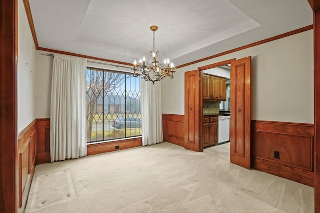 unfurnished dining area with a notable chandelier, a tray ceiling, ornamental molding, and light colored carpet