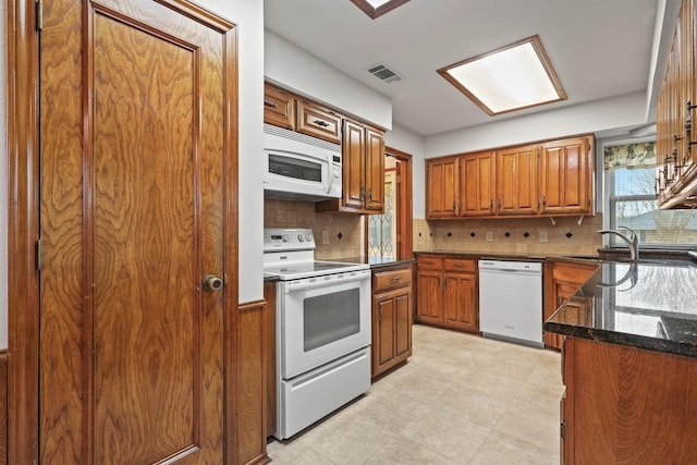 kitchen featuring tasteful backsplash, sink, white appliances, and dark stone counters