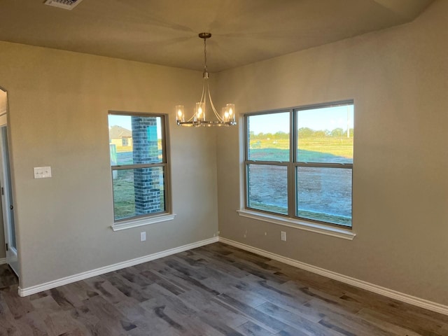 unfurnished dining area with dark hardwood / wood-style flooring, a wealth of natural light, and an inviting chandelier