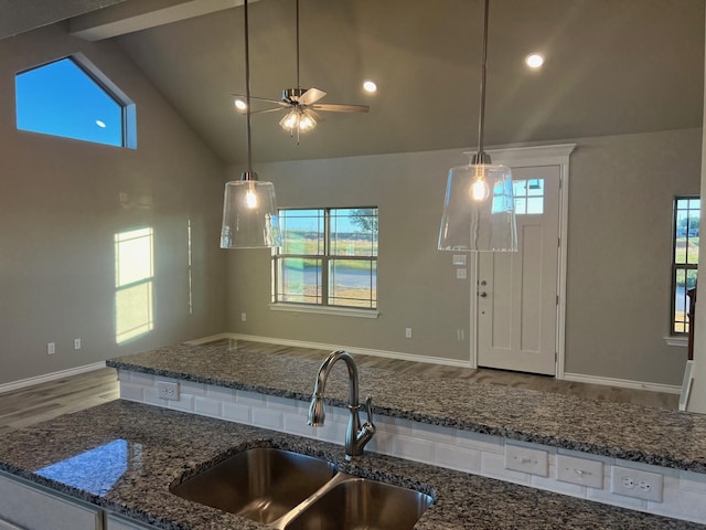 kitchen with hanging light fixtures, a healthy amount of sunlight, sink, and dark stone counters