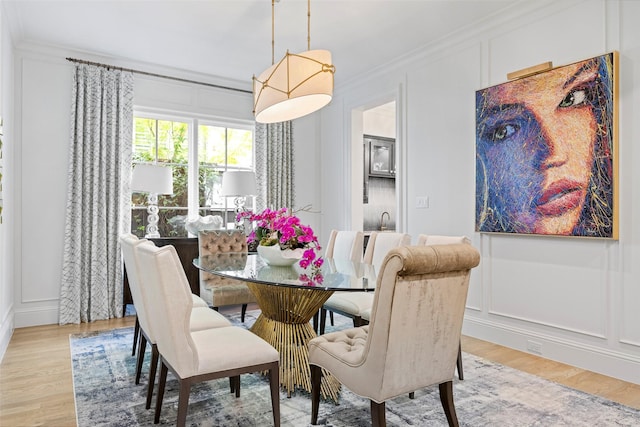 dining area with crown molding and light hardwood / wood-style floors