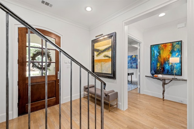 entrance foyer with ornamental molding and light hardwood / wood-style floors