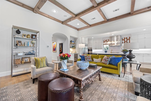 living room featuring coffered ceiling, sink, light hardwood / wood-style floors, and beamed ceiling