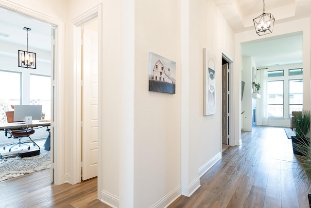 hall featuring wood-type flooring and a chandelier