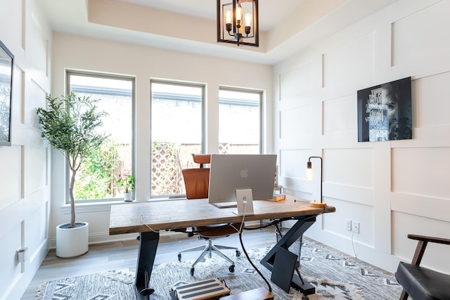 office area featuring a tray ceiling, a chandelier, and hardwood / wood-style floors