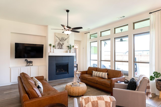 living room with hardwood / wood-style flooring, a tile fireplace, and ceiling fan