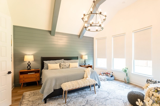 bedroom with beamed ceiling, wooden walls, a chandelier, and light wood-type flooring