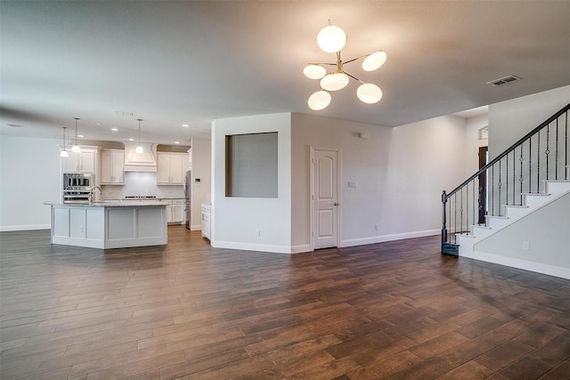 unfurnished living room with dark wood-type flooring, sink, and a notable chandelier