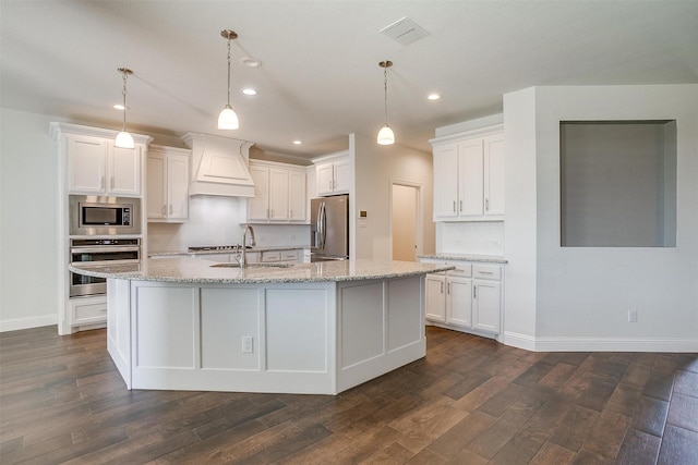 kitchen featuring white cabinetry, a center island with sink, custom exhaust hood, and appliances with stainless steel finishes