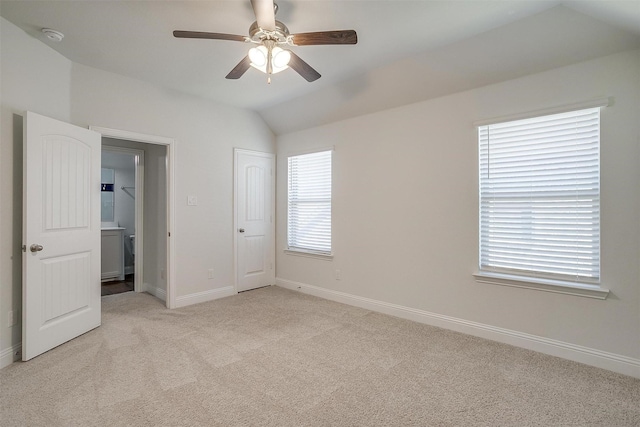 unfurnished bedroom featuring vaulted ceiling, light colored carpet, and ceiling fan